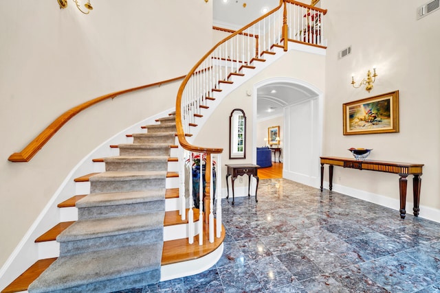 staircase with a towering ceiling, tile floors, and ornamental molding