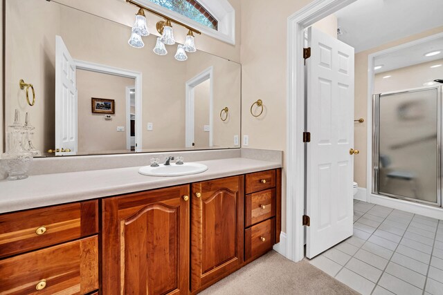 bathroom with a shower with door, vanity, tile floors, and toilet