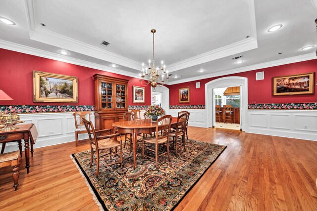 dining room with a chandelier, crown molding, light hardwood / wood-style flooring, and a tray ceiling