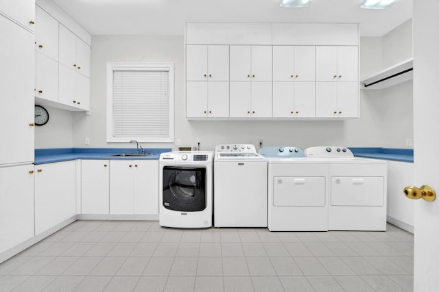 laundry area featuring washing machine and clothes dryer, cabinets, sink, and light tile flooring