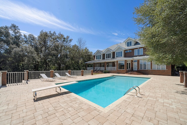 view of swimming pool with a patio area and a diving board