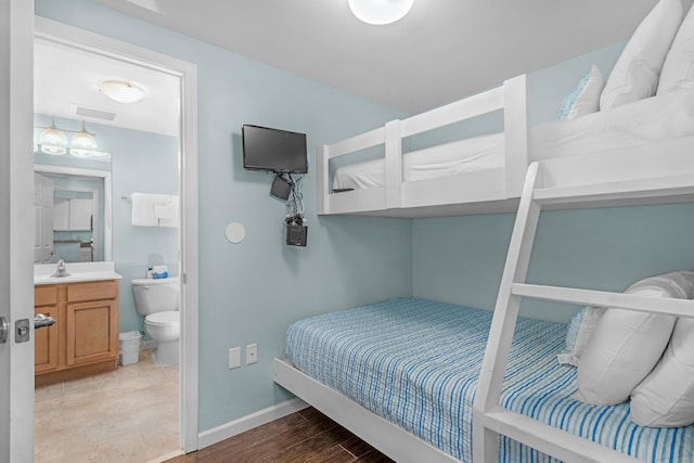 bedroom with ensuite bathroom, sink, and light wood-type flooring