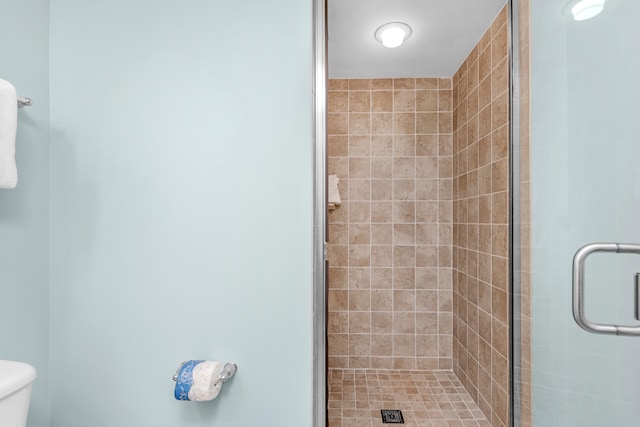 bathroom featuring a shower with door and toilet