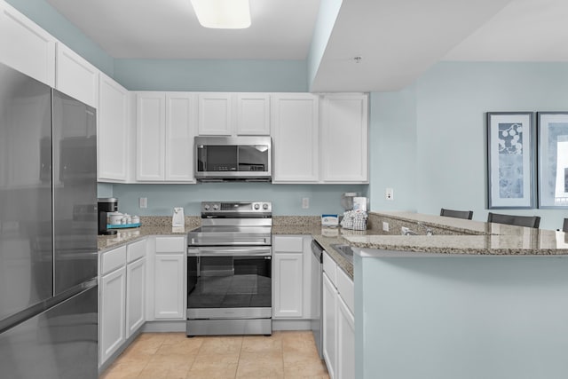 kitchen with kitchen peninsula, white cabinetry, stainless steel appliances, and light stone counters