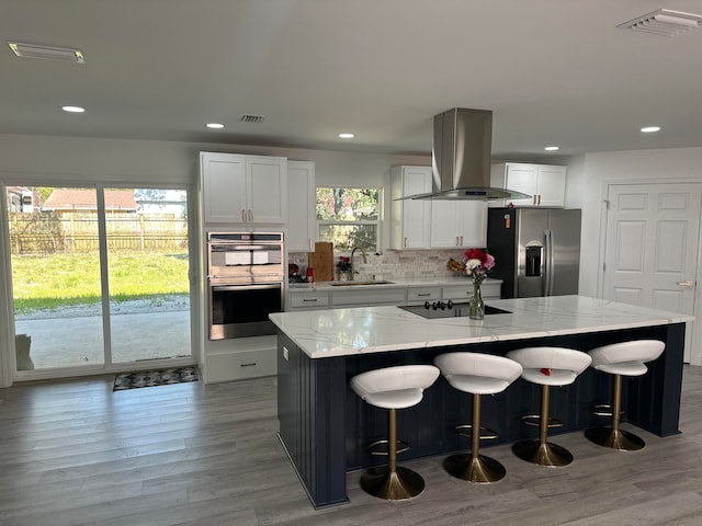 kitchen featuring island range hood, sink, white cabinets, stainless steel fridge with ice dispenser, and a center island