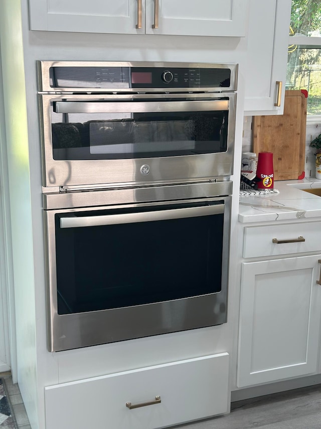 interior space featuring light stone countertops, white cabinets, and stainless steel double oven