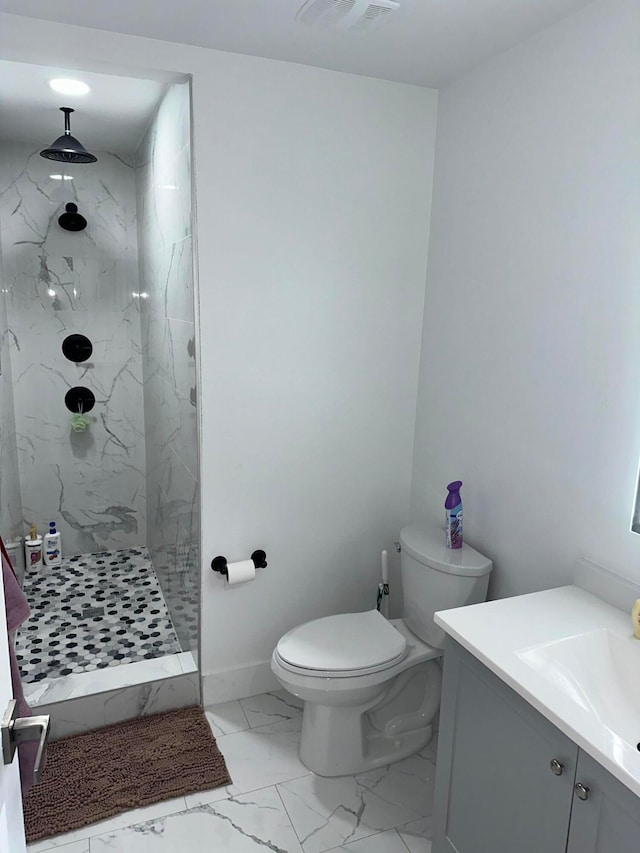 bathroom with vanity, toilet, and a tile shower