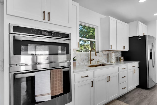 kitchen featuring light stone countertops, sink, white cabinetry, and stainless steel appliances