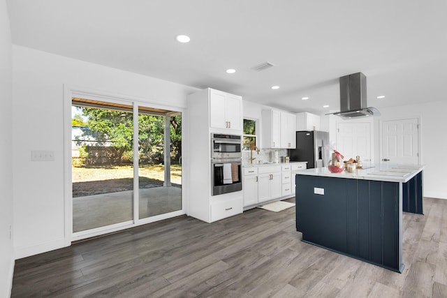 kitchen with stainless steel appliances, white cabinetry, a kitchen island, and island range hood