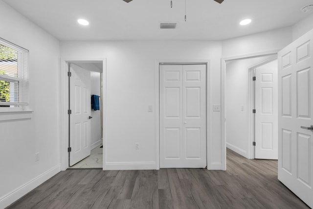 unfurnished bedroom featuring ensuite bathroom, ceiling fan, and dark wood-type flooring