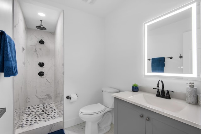 bathroom with a tile shower, vanity, and toilet