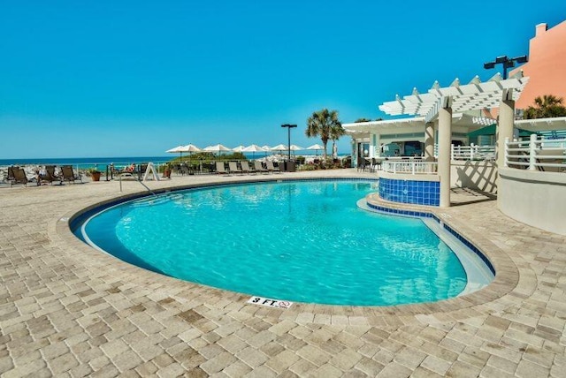 view of pool featuring a patio, a water view, and a pergola