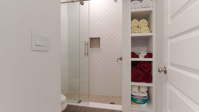 bathroom featuring a shower with shower door, tile floors, toilet, and built in shelves