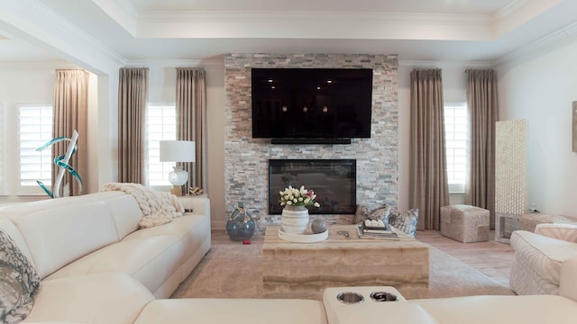 living room with a healthy amount of sunlight, a fireplace, a raised ceiling, and crown molding