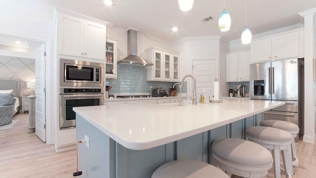 kitchen featuring a breakfast bar, tasteful backsplash, stainless steel appliances, and wall chimney exhaust hood