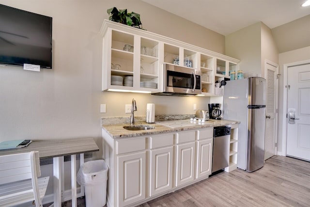 kitchen featuring light stone counters, sink, light wood-type flooring, white cabinetry, and stainless steel appliances