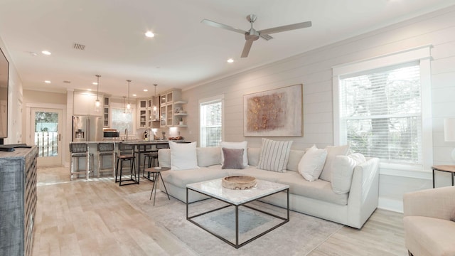 living room featuring light hardwood / wood-style flooring, ceiling fan, and ornamental molding