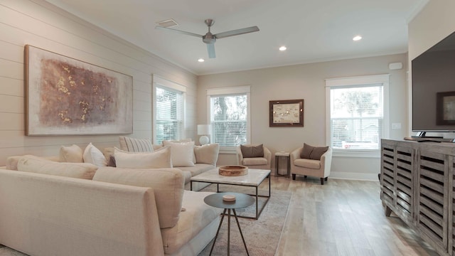 living room with ceiling fan, crown molding, light wood-type flooring, and a wealth of natural light