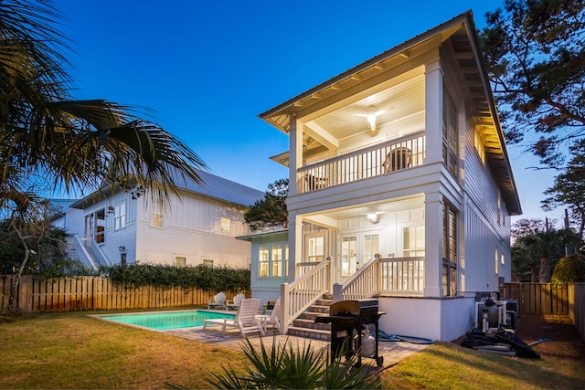 back of house with a yard, a balcony, a patio, and a fenced in pool