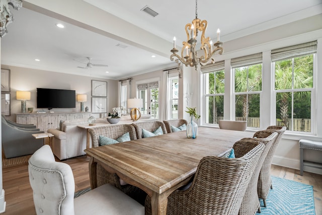 dining room with ceiling fan with notable chandelier, light hardwood / wood-style flooring, and a healthy amount of sunlight