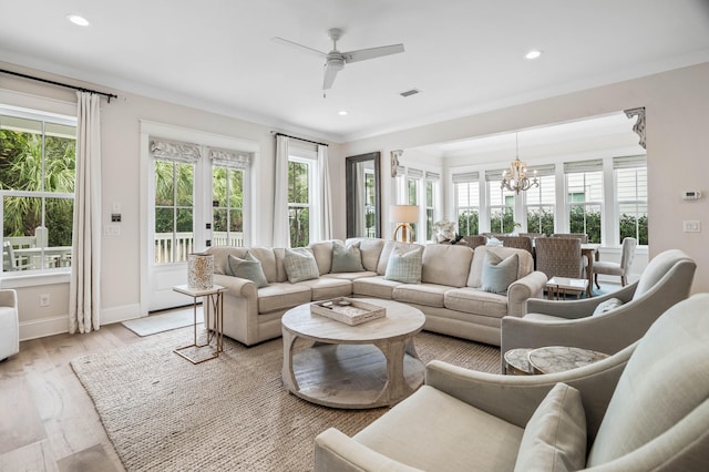 living room featuring a wealth of natural light, french doors, ceiling fan with notable chandelier, and light wood-type flooring