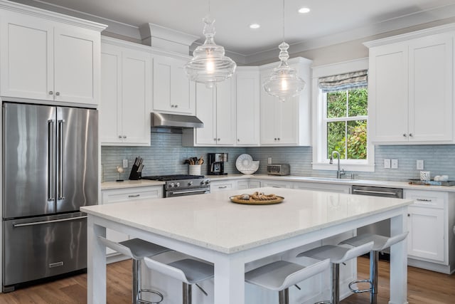 kitchen featuring hanging light fixtures, tasteful backsplash, premium appliances, and white cabinets