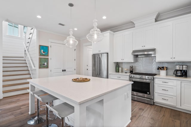 kitchen with wood-type flooring, stainless steel appliances, a center island, and decorative light fixtures