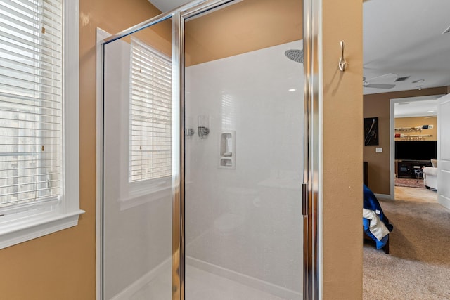 bathroom with walk in shower, ceiling fan, and a healthy amount of sunlight