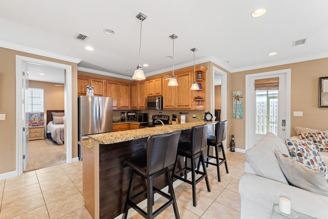 kitchen with appliances with stainless steel finishes, a wealth of natural light, light tile flooring, and light stone counters