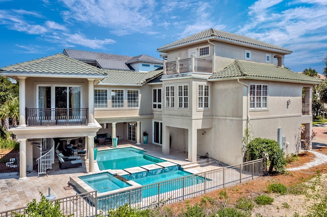 back of property with a patio, a pool with hot tub, and a balcony