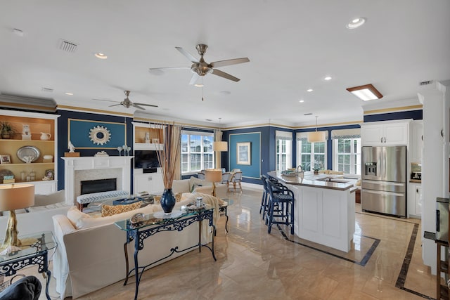 living room with a wealth of natural light, ornamental molding, ceiling fan, and light tile flooring