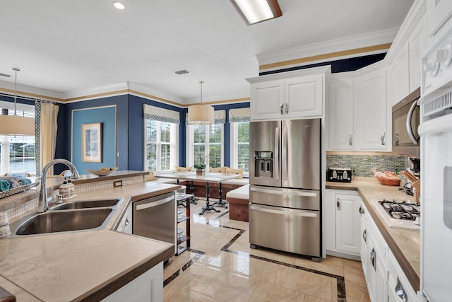 kitchen with sink, hanging light fixtures, white cabinetry, and stainless steel appliances