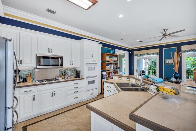 kitchen featuring white cabinetry, stainless steel appliances, light tile floors, sink, and ceiling fan