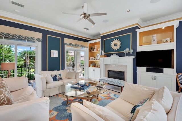 living room featuring built in features, plenty of natural light, crown molding, and ceiling fan