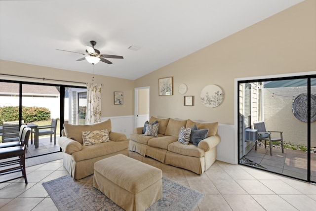 living room featuring lofted ceiling, a wainscoted wall, light tile patterned flooring, and a ceiling fan