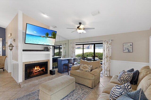 living room with ceiling fan, light tile patterned flooring, and a tile fireplace