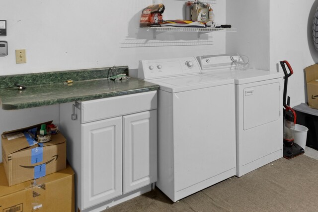 laundry room with washing machine and clothes dryer, cabinets, and light colored carpet