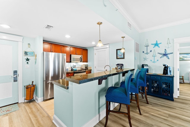 kitchen featuring crown molding, stainless steel appliances, light hardwood / wood-style floors, decorative light fixtures, and kitchen peninsula