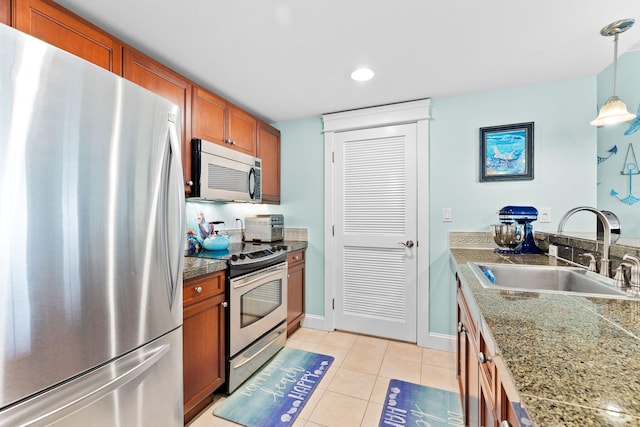 kitchen with sink, light tile patterned floors, hanging light fixtures, and appliances with stainless steel finishes