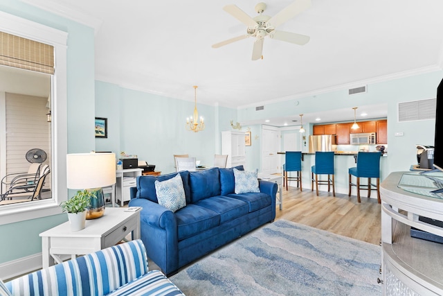 living room featuring ornamental molding, ceiling fan with notable chandelier, and light hardwood / wood-style flooring