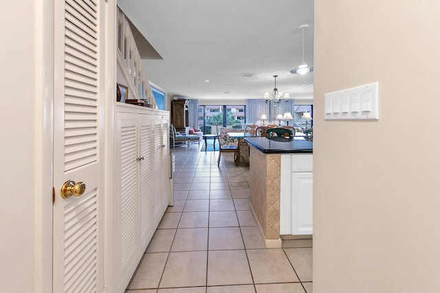 kitchen featuring pendant lighting, light tile floors, a chandelier, and white cabinetry