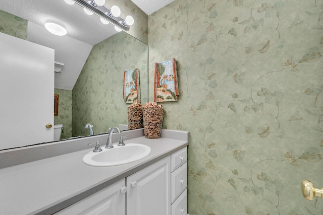 bathroom featuring vanity, vaulted ceiling, a textured ceiling, and toilet