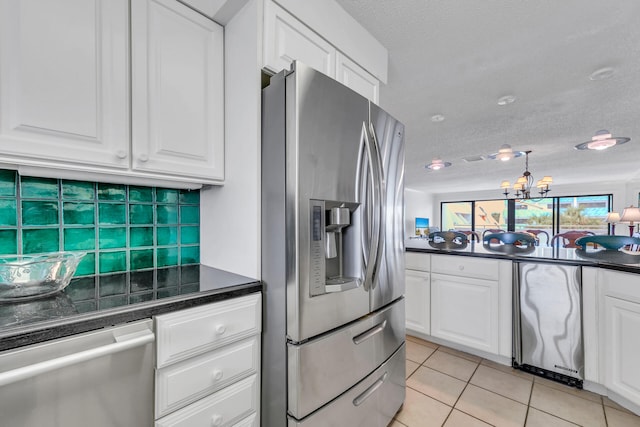 kitchen with light tile patterned floors, appliances with stainless steel finishes, white cabinetry, tasteful backsplash, and a textured ceiling