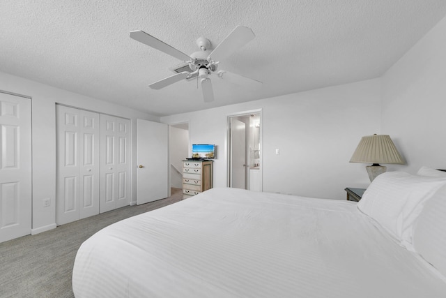 carpeted bedroom with ceiling fan, two closets, and a textured ceiling