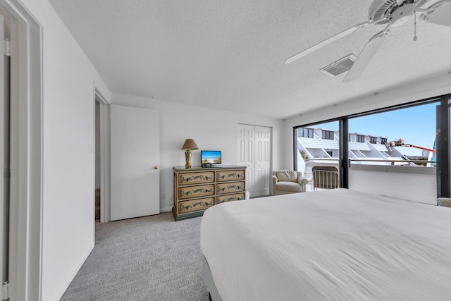 bedroom featuring ceiling fan, a closet, light carpet, and a textured ceiling