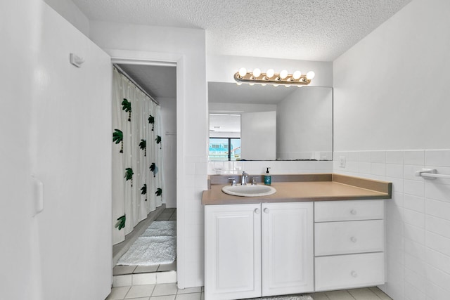 bathroom featuring tile walls, vanity, tile patterned floors, and a textured ceiling