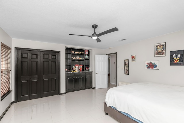 bedroom with ceiling fan, a textured ceiling, and bar