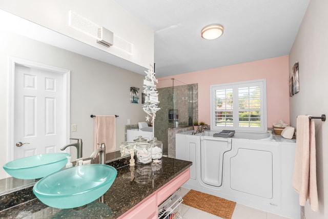 bathroom with tile patterned flooring, vanity, washing machine and dryer, and separate shower and tub