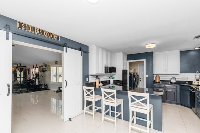 kitchen featuring tasteful backsplash, light tile patterned floors, white cabinetry, and stainless steel appliances