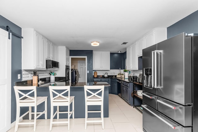 kitchen featuring a breakfast bar area, a barn door, white cabinetry, and high end fridge